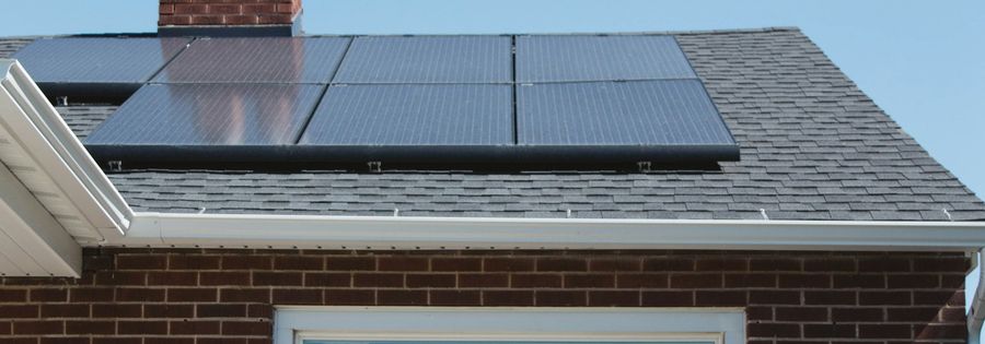 Black solar panels on the slate roof of a red brick house